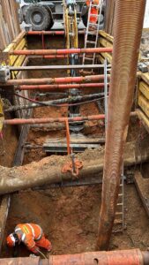 Ouvrier Novello dans une tranchée sécurisée par un blindage et des étais sur un chantier d'excavation.