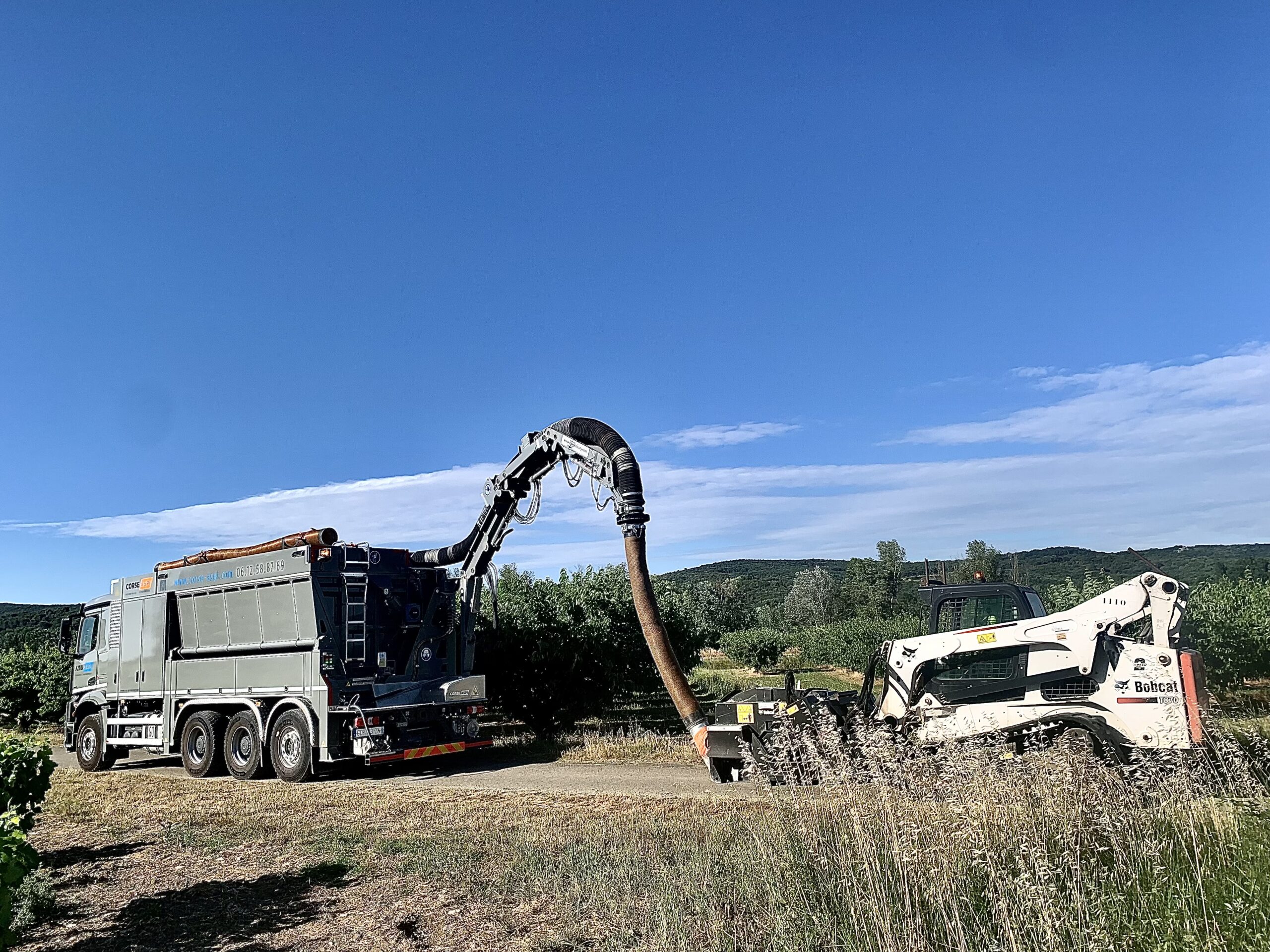 Camion aspiratrice excavatrice Corse Aspi avec Bobcat T870 lors de travaux agricoles ou de terrassement.