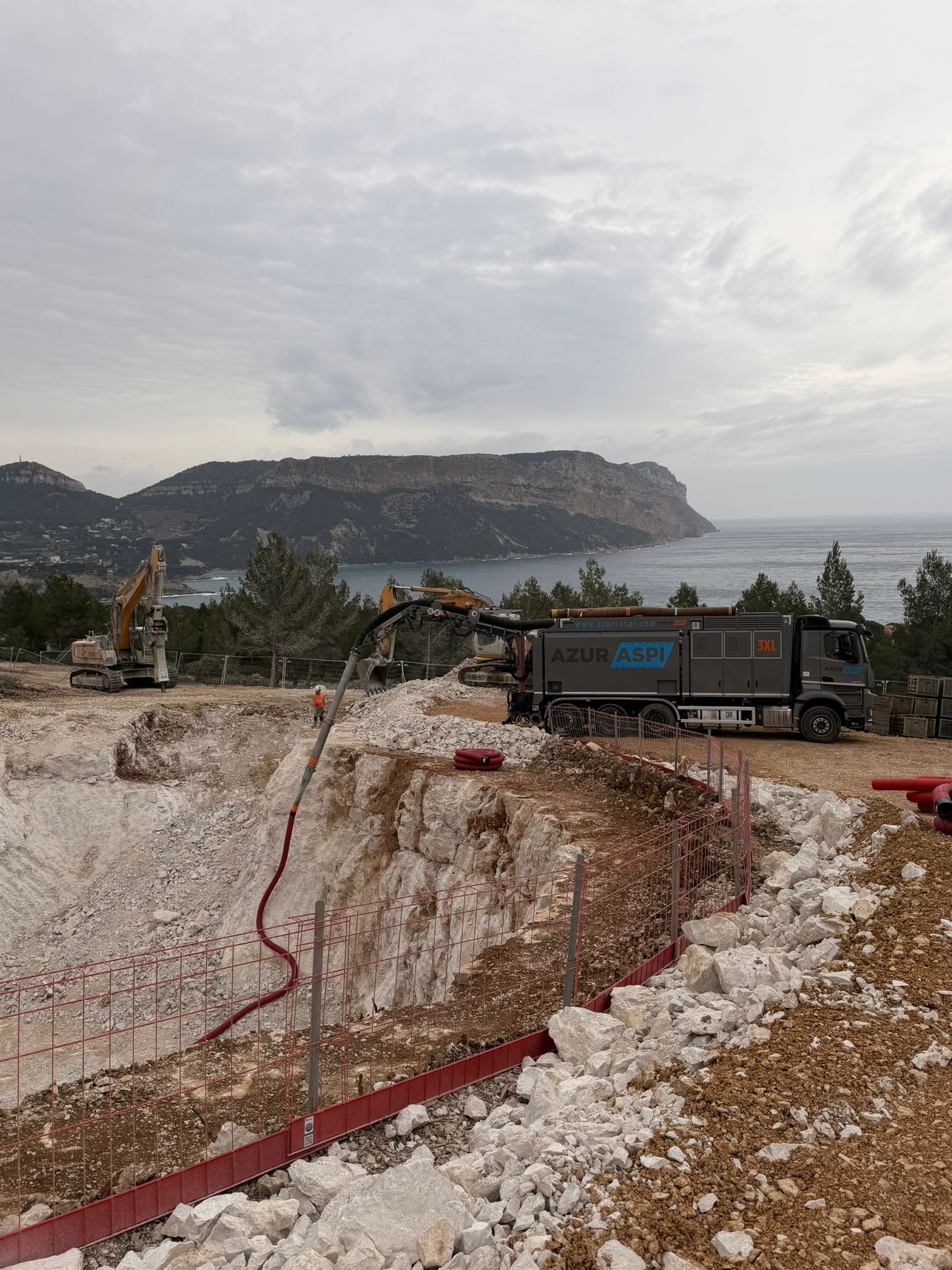 Camion aspirateur Azur Aspi 3XL en action sur un chantier d'excavation surplombant la mer et les falaises.