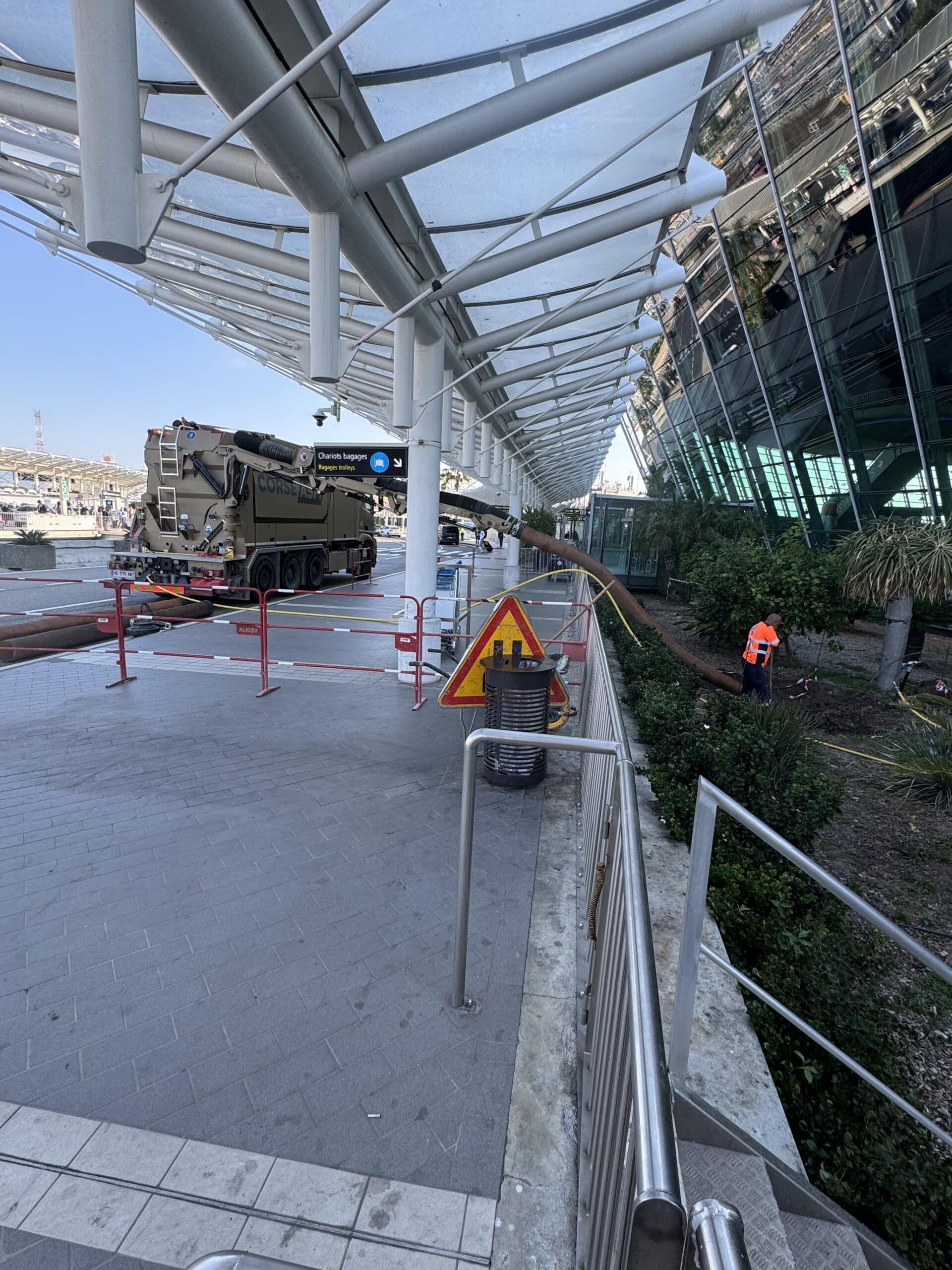 Camion aspirateur Corse Aspiration en intervention à l'aéroport avec ouvrier près de la zone des chariots bagages.