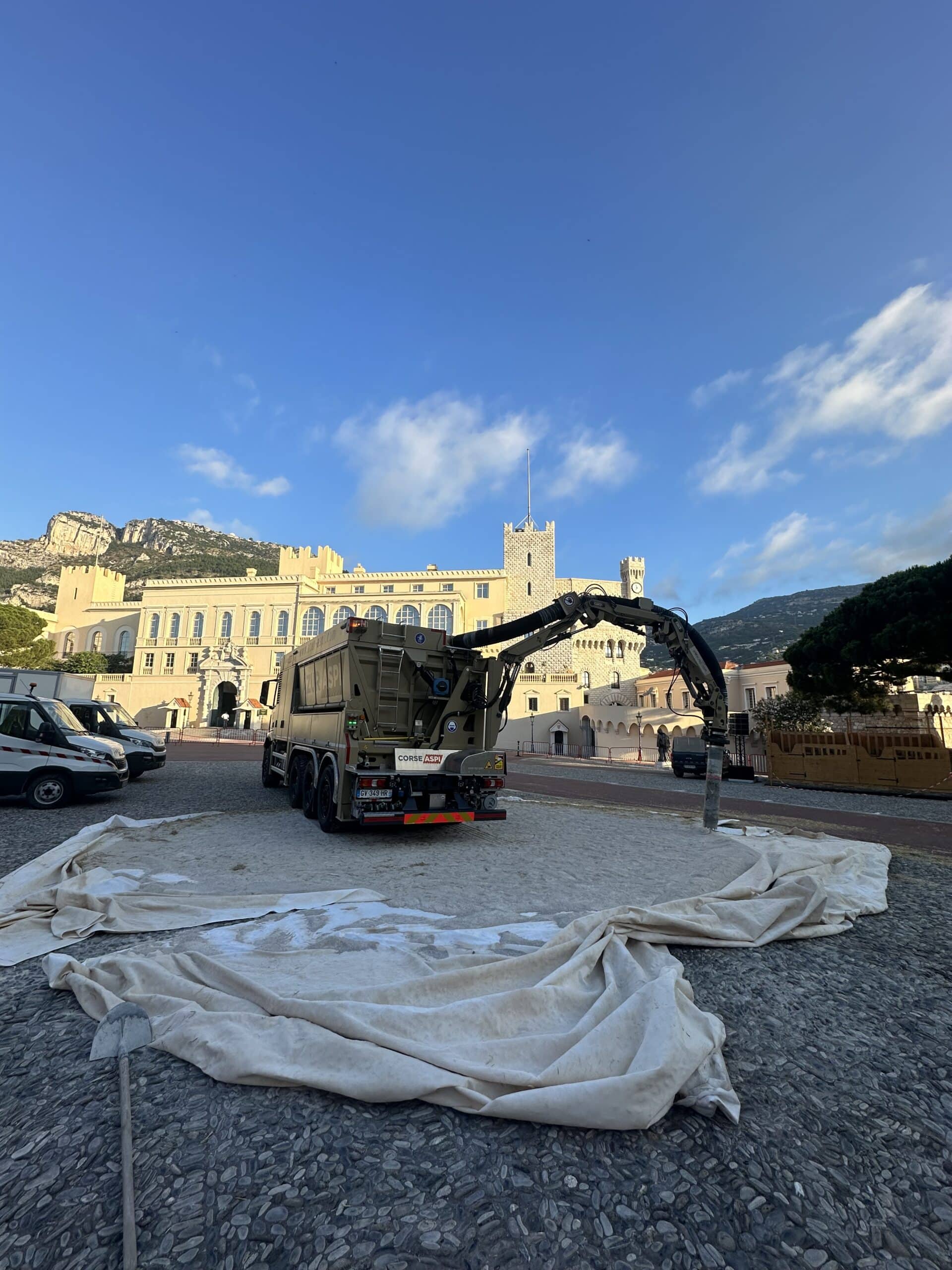 Camion Corse Aspi en intervention sur la place du Palais de Monaco, bâche blanche et bras articulé.