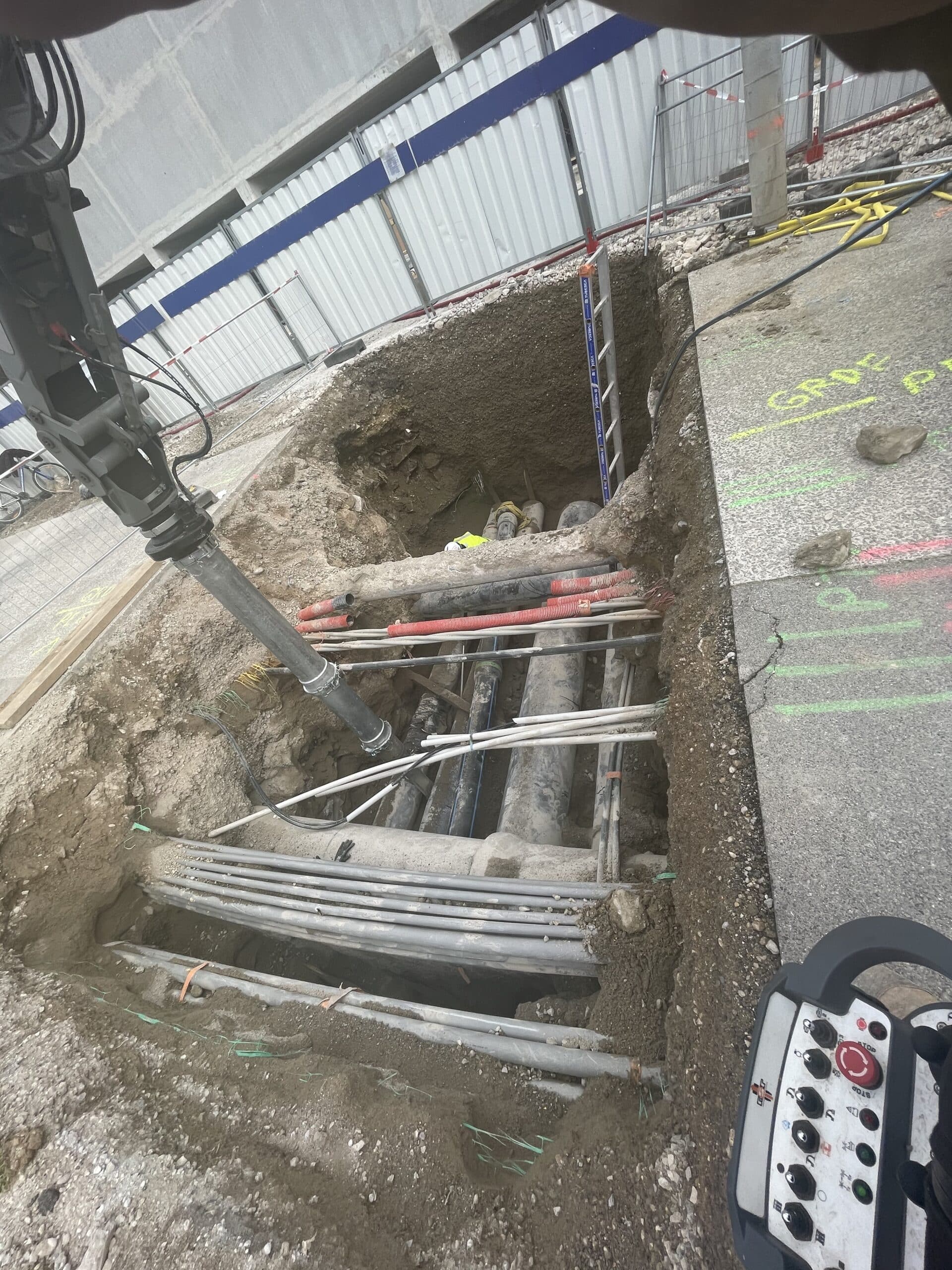 Camion aspirateur dégageant des réseaux enterrés et tuyaux dans une tranchée profonde sur un chantier de travaux publics.