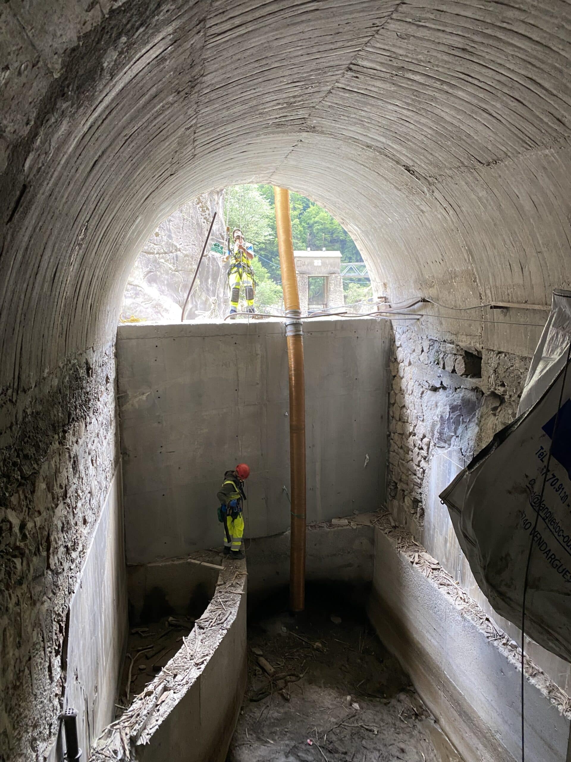 Ouvriers en tenue de sécurité travaillant dans un tunnel bétonné avec un conduit orange et harnais à Vendargues.